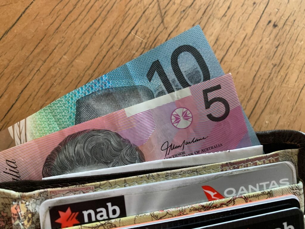 pexels photo 7654007 7654007 Close-up of Australian dollar bills and credit cards in a wallet on a wooden surface.